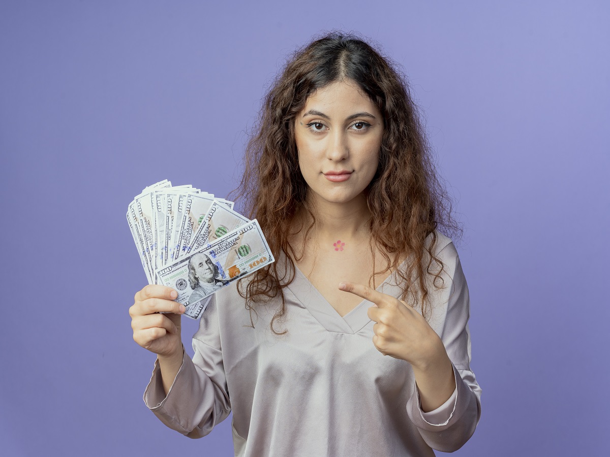 looking-camera-young-pretty-girl-holding-points-cash-isolated-blue-background